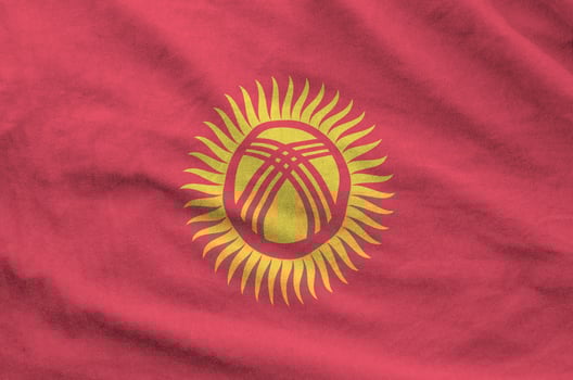 Kyrgyzstan flag depicted on folded wavy fabric of old cloth photo