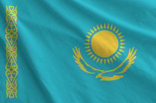Kazakhstan flag depicted on folded wavy fabric of old cloth photo
