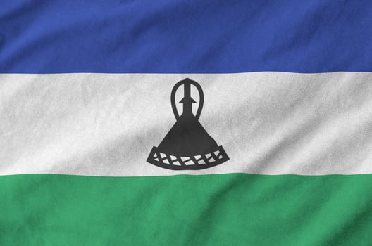 Lesotho flag depicted on folded wavy fabric of old cloth photo