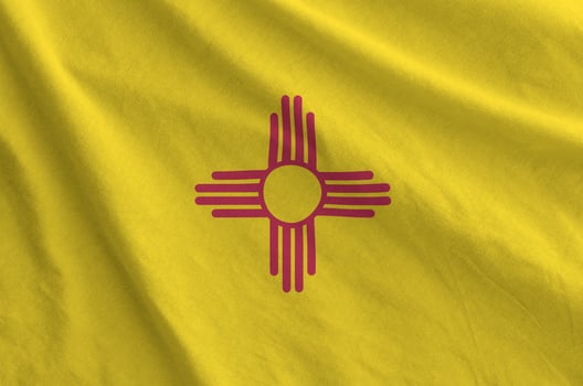 New Mexico US state flag depicted on folded wavy fabric of old cloth photo
