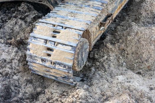Close-up of excavator caterpillars on rough terrain, showcasing detailed treads and dirt accumulation. Ideal for construction and machinery themes. photo