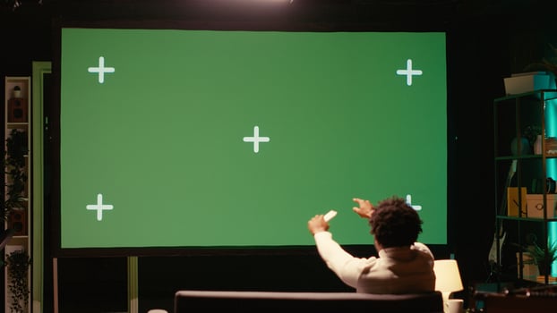African american man watching football competition live on widescreen chroma key smart TV, cheering for favorite team. Sports fan on couch in front of green screen television set celebrating goal photo
