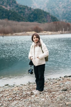 Woman tourist travel Kamikochi National Park, happy Traveler sightseeing Taisho pond with mountain, Nagano Prefecture, Japan. Landmark for tourists attraction. Japan Travel, Destination and Vacation photo