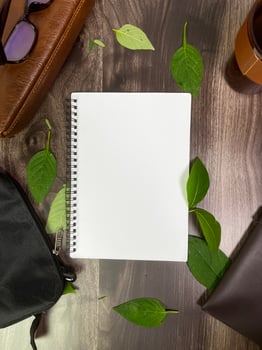 Still life photography blank notebook on wooden table with a cup of coffee, plant, leaf on table photo