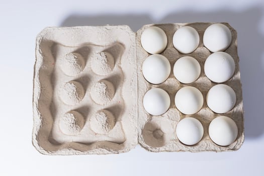 Chicken white eggs in a carton box on a white background. photo