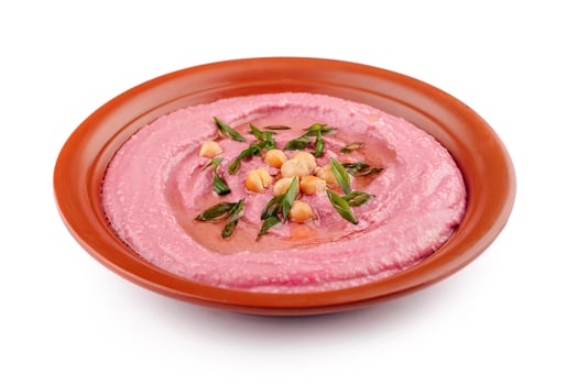 Beetroot hummus decorated with chickpeas and green onions in a clay dish photo
