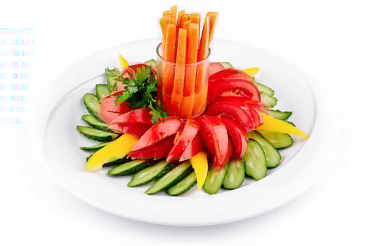 Fresh vegetables arranged on plate forming flower shape with carrots in the middle photo
