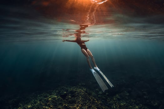 Woman freediver relaxing on surface of ocean after diving. Woman freediving on morning with warm sun light photo