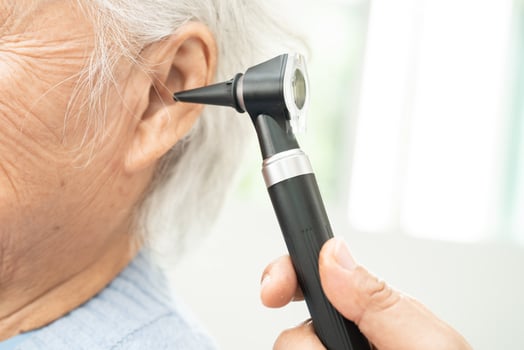 Audiologist or ENT doctor use otoscope checking ear of asian senior woman patient treating hearing loss problem. photo