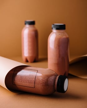 Chocolate protein shake in bottles with blank labels for mockup on brown background photo
