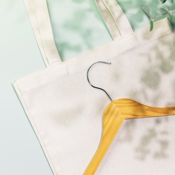 Wooden hanger on textile shopping bag on blue background photo