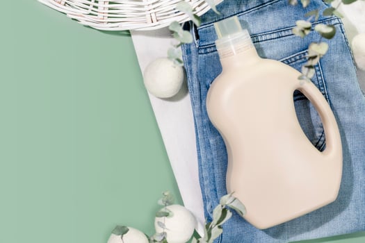 Bottle of washing gel on clothes with laundry balls on green background photo