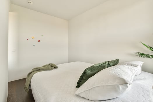 A bedroom with a white bed and wooden floor photo