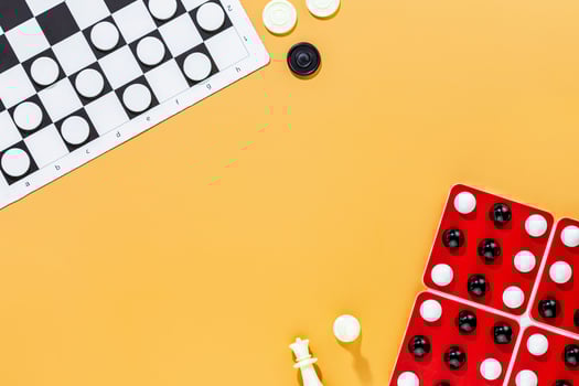 Various board games with chess pieces and checkers on orange background photo