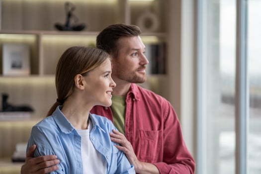 Calm relaxed married couple standing with gentle embrace looking to window together enjoys slow life photo