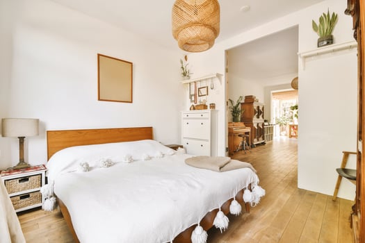 A bedroom with a bed, a dresser and a wooden floor photo