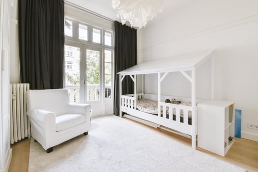 A white bedroom with a wooden bed and a chair photo