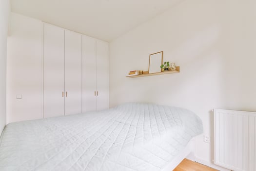 A bedroom with a bed and a shelf with a picture on it photo