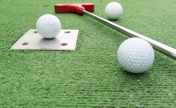 Fun vacation entertainment for summertime. Playing mini golf on green grass outdoors. Setting goals and winning lifestyle concept. Competition at golf course. two crossed sticks. Blank space for copy. photo