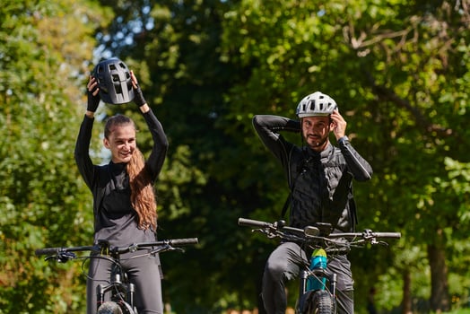 A blissful couple, adorned in professional cycling gear, enjoys a romantic bicycle ride through a park, surrounded by modern natural attractions, radiating love and happiness photo