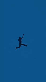 Silhouette of a Man Jumping Against a Blue Sky photo