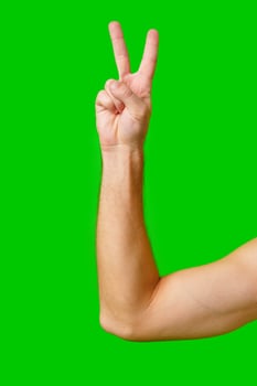 Hand Gesture of Peace Made Against a Bright Green Background photo