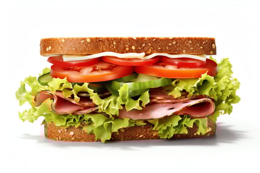 Photo of a sandwich with ham, cheese, tomato, cucumber, and lettuce on whole wheat bread. The sandwich is cut in half and sitting on a white background.