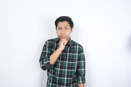 serious asian young man thinking about future with hand on chin isolated photo