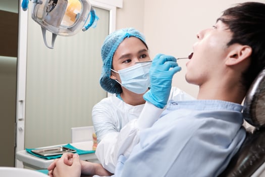 Asian female dentist examine young male patient teeth and toothache stomatology in dental clinic, well-being hygiene checks, and professional orthodontic healthcare work in doctor's office hospital. photo