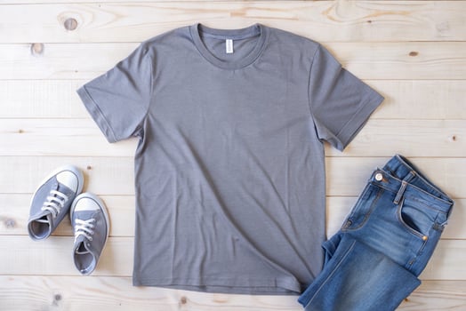 Grey t - shirt, jeans and sneakers on wooden floor photo