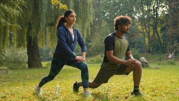 Confident determined Indian couple Arabian man woman girl guy doing lunges squats exercises sport morning workout in park outdoors fit friends people team sports body weight training personal coach photo