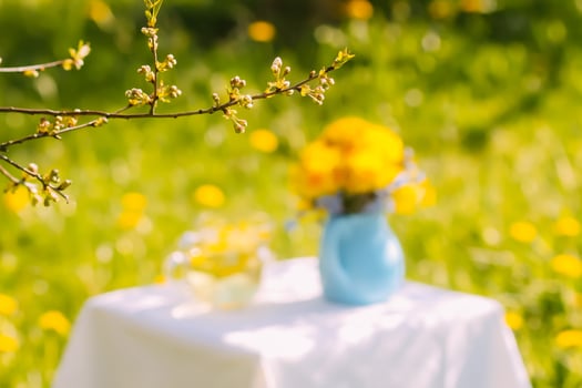 Herbal tea in a glass cup. Dandelion flowers in ceramic jug. photo