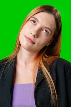 Young Woman Wearing Black Blazer and Purple Top Against Green Screen photo