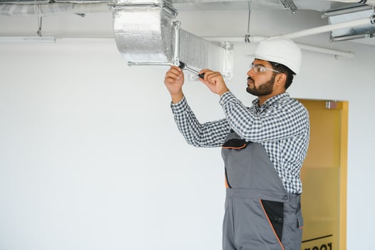 An Indian worker inspects the ventilation system in an office building photo