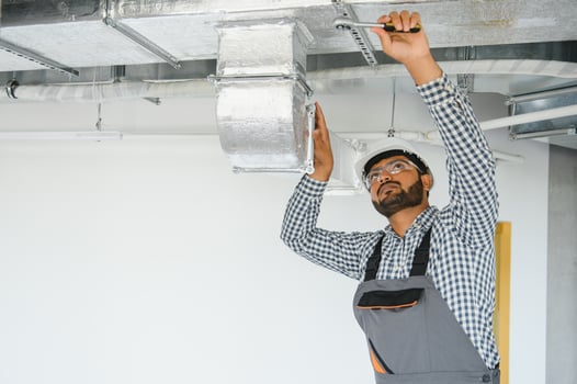 An Indian worker inspects the ventilation system in an office building photo