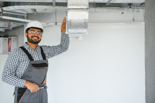 hvac indian worker install ducted pipe system for ventilation and air conditioning. copy space photo