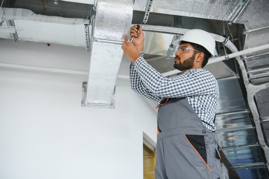 hvac indian worker install ducted pipe system for ventilation and air conditioning. copy space photo