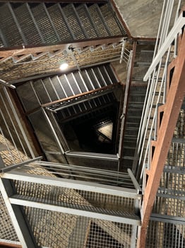 A spiraling metal staircase inside a church tower, leading upwards to the top. photo