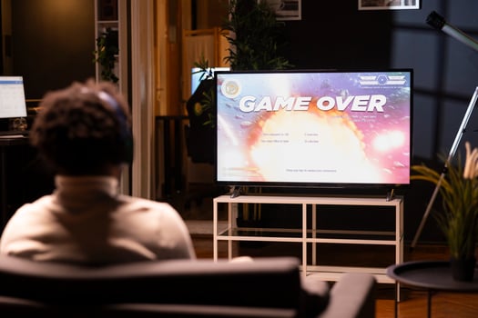 Man looking at game over screen of science fiction videogame on smart TV. African american gamer receiving defeat message after failing to beat level, watching statistics roll on display photo
