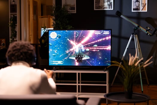 African american man in home theatre using cloud gaming service to play demanding science fiction videogame on TV. Gamer enjoying high quality graphics, streaming game over the internet photo