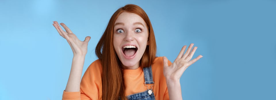 Surprised astonished sensitive overwhelmed young happy redhead girl receive incredible fantastic prize wide eyes astonished raising hands triumphing win lottery celebrating joyfully photo