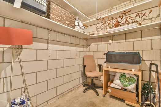 A small room with a desk, chair and shelves photo