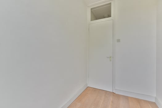 A white room with a door and wooden floor photo