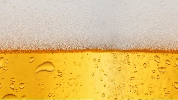 Close-up of yellow beer with rich foam and water droplets on a white background, perfect for refreshing beverage visuals photo
