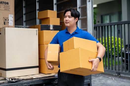 A delivery guy is carrying boxes from his truck to deliver to a customer in front of their house. photo