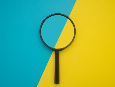 Top view of a magnifying glass isolated on blue and yellow background. Search concept photo