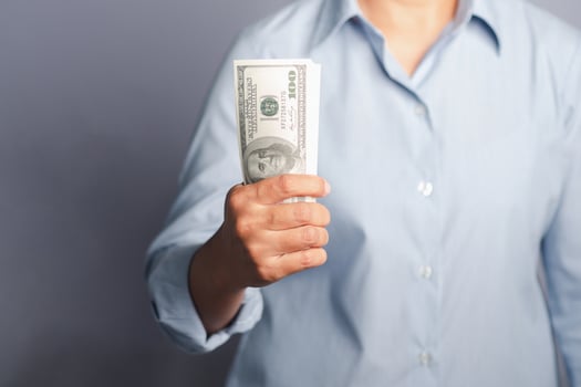 Business and finance concept. Hand holding of a US dollars banknote while standing on gray background in the studio. Close-up photo. Space for text photo