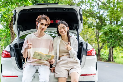 Traveler couple on road trip, man and woman sitting together in car trunk using map on journey during the trip, Two young boy and girl travel, Two friend traveling on vacation, searching road in map photo