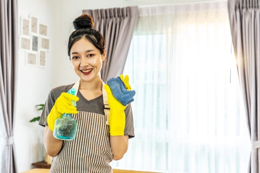 Happy young housewife mistress female in yellow protective rubber gloves with spray and rag,cleaning house, enjoying housework, Asian maid committed to maintaining the highest standards of cleanliness photo