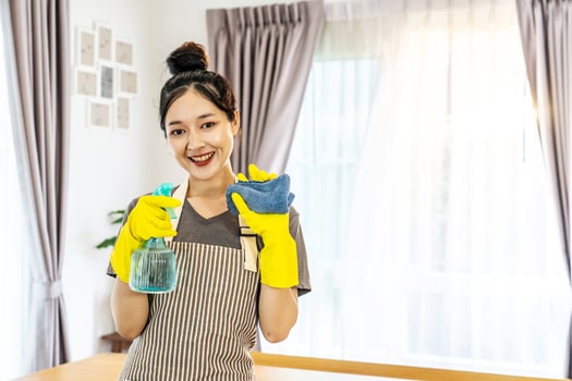 Happy young housewife mistress female in yellow protective rubber gloves with spray and rag,cleaning house, enjoying housework, Asian maid committed to maintaining the highest standards of cleanliness photo
